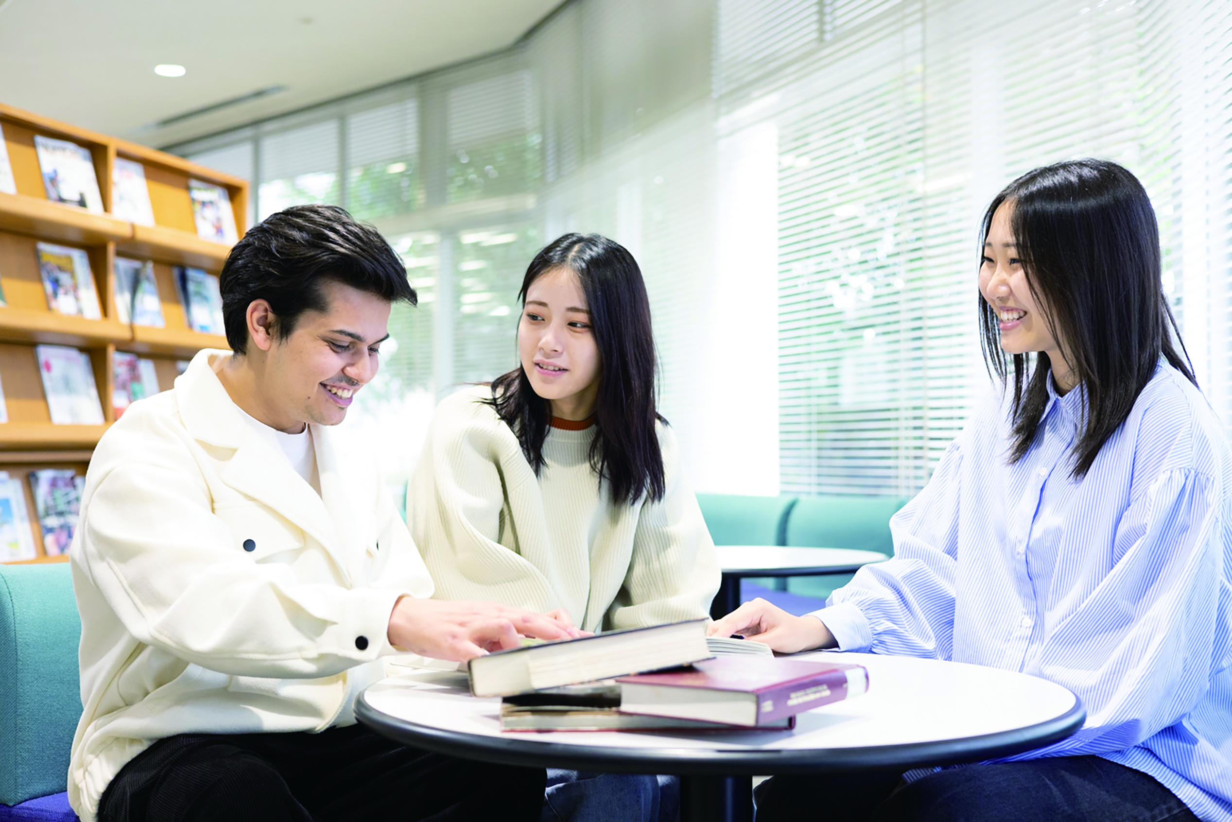 図書室で本を囲みながら会話する多国籍の学生グループ。