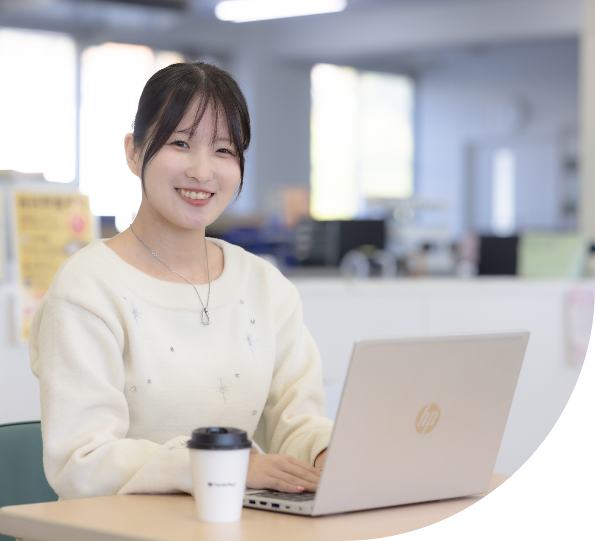 ノートパソコンで作業をしながら笑顔を見せる女性