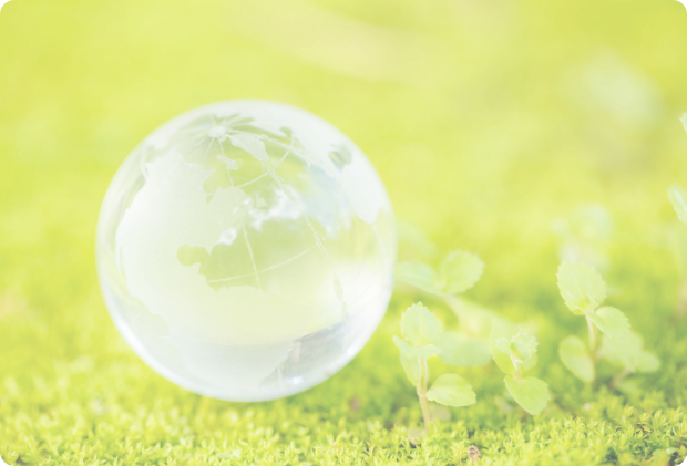 苔の生えた緑の上に置かれた、光を反射する透明なガラスの地球儀